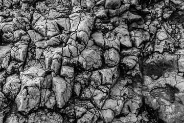Black and white close view of fractured coastal rock surface with natural fissures