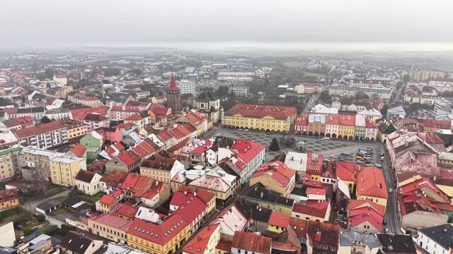 aerial view red tiled rooftops market square church tower, overcast sky, pastel facades, cobblestone streets,