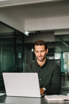 European businessman entrepreneur using computer technology app for work or online learning. Young professional specialist latin hispanic business man working on laptop pc at desk in office. Vertical
