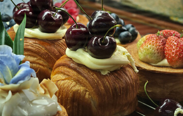 Freshly baked pastries topped with whipped cream and fresh cherries.