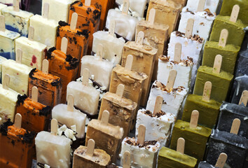 A variety of ice cream flavors are available in the display case, served on sticks.