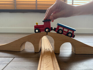 hand pushing toy train on wooden bridge, home floor, concept of education, childhood, play, banner