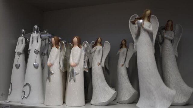 White angel figurines standing on store shelf with silver wings and heart details creating calm holiday decor atmosphere in christmas home decoration section