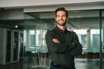 Corporate portrait of European confident student, trade manager businessman standing crossed arms...