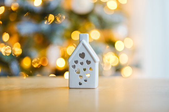 Minimalist white ceramic house with heart cutouts and warm Christmas bokeh lights