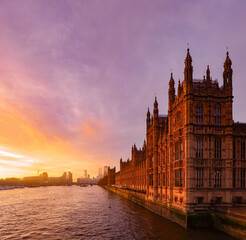 Obraz premium Palace of Westminster and River Thames at sunset, London cityscape glowing under a vibrant orange and purple sky