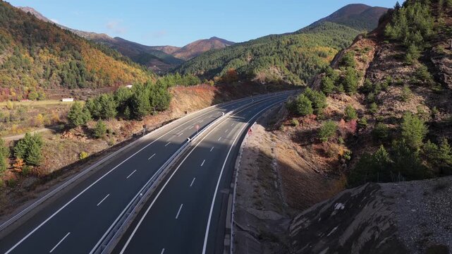 Aerial video of the A1 motorway winding through the mountain valleys of Mirdita, surrounded by autumn forests and scattered hillside homes in Northern Albania. 