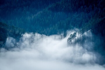 mountain landscape with high mountain peaks in snow and a foggy valley down