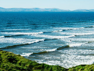 Powerful ocean waves and rich blue water of the ocean, Bundoran town, Ireland. Popular tourist area with stunning view and surfing area. Warm sunny day. Travel and tourism. Irish landscape.