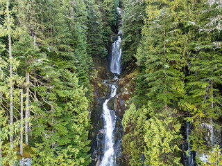 Tall Mountain Waterfall Surrounded by Lush Green Forests in British Columbia, Canada: Nature Wilderness Scene