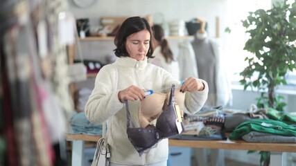  While shopping, woman looks at products in store and selects brassiere. Concept of seasonal wardrobe shopping. Client at shopping time leisure activity. 