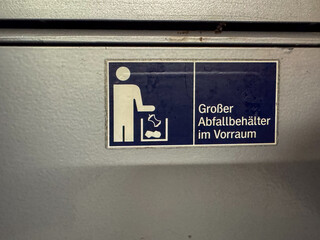 Person disposing trash in a large german waste bin