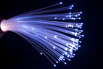 A close-up shot of a bundle of fiber optic cables glowing with bright blue and white light at the tips against a pitch-black background. This imagery symbolizes high-speed internet technology.