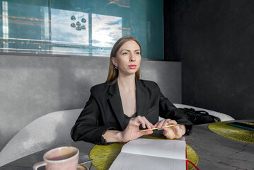 A girl sits at a table with a thoughtful face over a sketchpad.