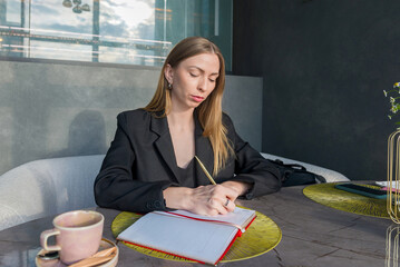 A girl sits at a table with a thoughtful face over a sketchpad.