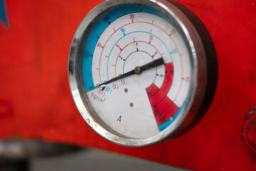 Close-up of analog pressure gauge with colored safety zones and numerical scale for automotive diagnostics
