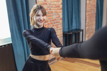 Young woman enjoying a dancing class session in a bright studio with students