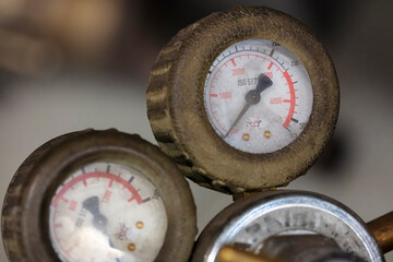 Group of worn industrial pressure gauges with rubber protective covers displaying measurement scales and brass connections
