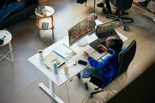 High angle view of male programmer working on desktop PC in tech startup office