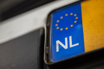 Macro detail of Netherlands vehicle license plate showing European Union stars and NL identifier with selective focus depth