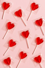 Heart shaped red lollipops on pink background. Playful Valentine&rsquo;s Day candy pattern symbolizing love, sweetness and cheerful celebration