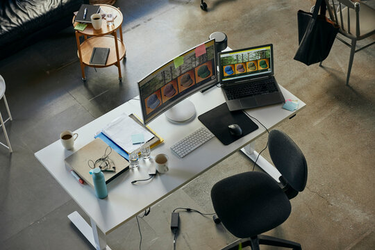 High angle view of images seen on computers at desk in startup tech office