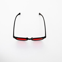 Minimalist top-down shot of red lens eyewear with black frame, designed to block blue light at night and improve sleep quality.