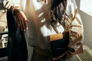 MIdsection of female tech professional holding file folder while standing in office