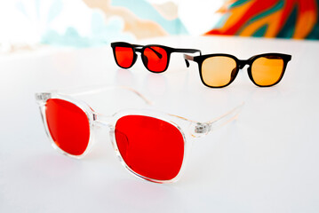 Modern eyewear with red and amber tinted lenses designed for blue light filtering, eye strain relief, and digital wellness, displayed in a clean studio setting.
