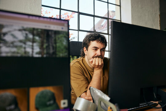 Focused male tech professional leaning on elbows while working in startup office