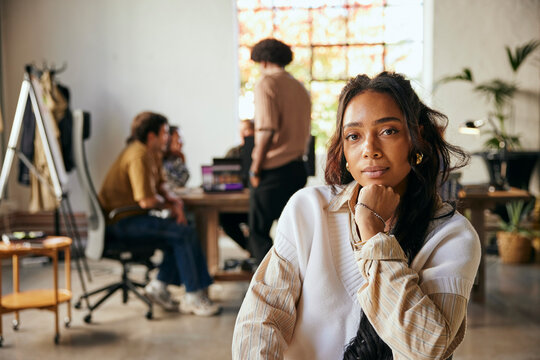 Portrait of confident female tech entrepreneur leaning on elbow while sitting in startup office