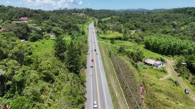 Rodovia que atravessa Mogi das Cruzes no sentido do litoral paulista, em dia de sol, cercada por &aacute;reas verdes e natureza, representando mobilidade, transporte e conex&atilde;o regional.