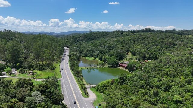 Estrada em meio &agrave; vegeta&ccedil;&atilde;o nativa destaca infraestrutura de transporte integrada &agrave; paisagem natural e &agrave; mobilidade regional.