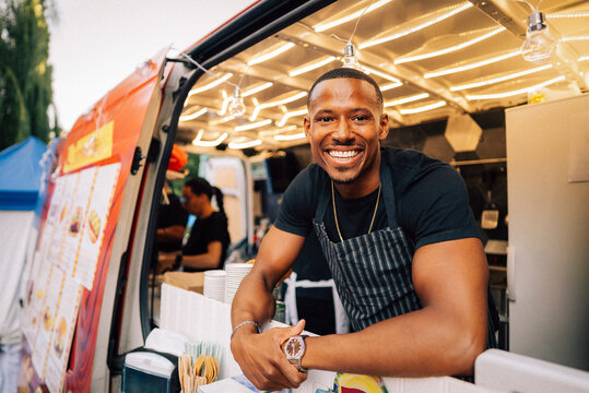 Portrait of smiling male business owner wearing apron standing in food truck