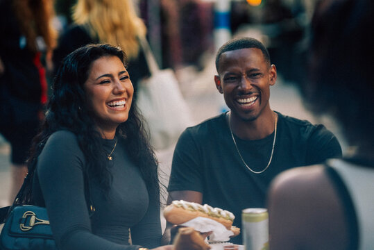 Happy male and female friends enjoying fast food at street