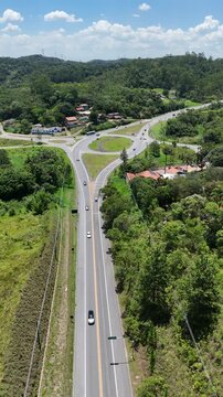 Rotat&oacute;ria rodovi&aacute;ria em meio a vegeta&ccedil;&atilde;o nativa, mostrando tr&aacute;fego controlado, integra&ccedil;&atilde;o vi&aacute;ria e a presen&ccedil;a de &aacute;reas verdes no entorno urbano.