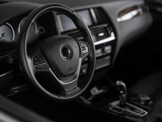 Black and white image of premium vehicle interior featuring leather steering wheel and modern dashboard design