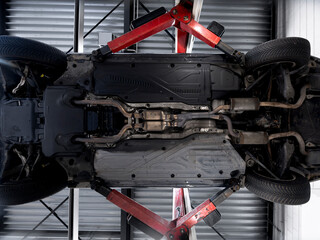Fototapeta premium Electric vehicle undercarriage showing battery pack exhaust system and suspension components during professional service inspection
