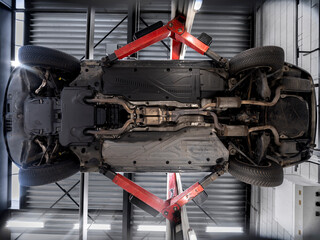Full vehicle underside view on hydraulic lift displaying mechanical systems and components during workshop inspection