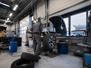 Mechanic performing tire balancing procedure using specialized equipment in modern automotive service facility