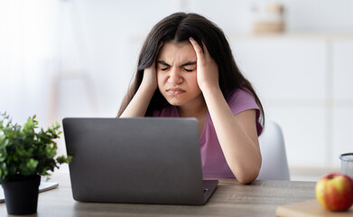 Exhausted Indian teen girl suffering from headache, having migraine, overworking, having too much...