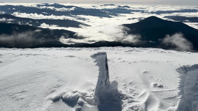 View from Hoverla in winter, Ukraine, Carpathians. Beautiful landscape with blue Carpathian peaks, morning fog in the gorges of Transcarpathia. Snow figures on a peak.