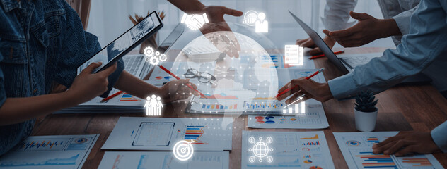 A collaborative business meeting featuring team members discussing data analysis, digital tools, and strategic planning in a modern workspace filled with technology. Trope