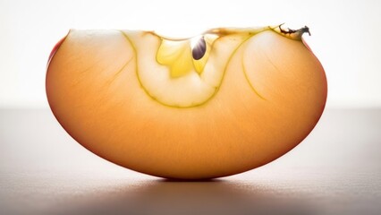 Close-up of a translucent apple slice, backlit with visible core details, resting on surface