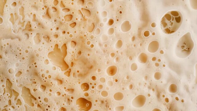 Foamy Beverage's Bubbles and Texture: The close-up shot captures the complex, bubbly texture of a light-colored, foamy beverage. The image draws in viewers with its details and shades.