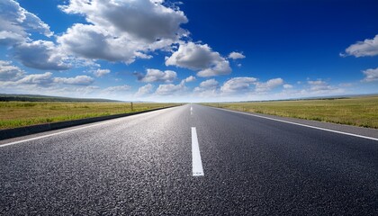 empty asphalt road stretches under a vibrant blue sky dotted with fluffy white clouds