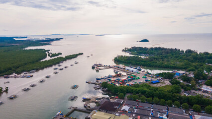 Aerial view of Tanjung Pandan Port featuring shipping containers and cargo boats at the Cerucuk River estuary, in Belitung Regency, Indonesia. A logistics hub surrounded by lush green mangroves.