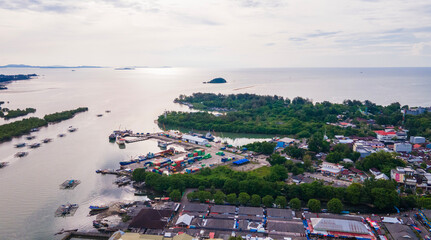 Aerial view of Tanjung Pandan Port featuring shipping containers and cargo boats at the Cerucuk River estuary, in Belitung Regency, Indonesia. A logistics hub surrounded by lush green mangroves.