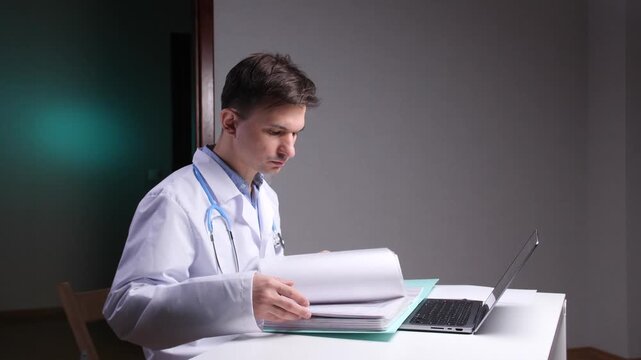 Doctor wearing a lab coat and stethoscope, analyzing patient medical records and paperwork at a desk in a medical office, focusing on essential healthcare documentation