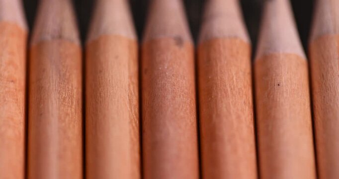 a group of wooden pencils with a black lead on a pine board , stacked pencils made of wood and a lead made of graphite